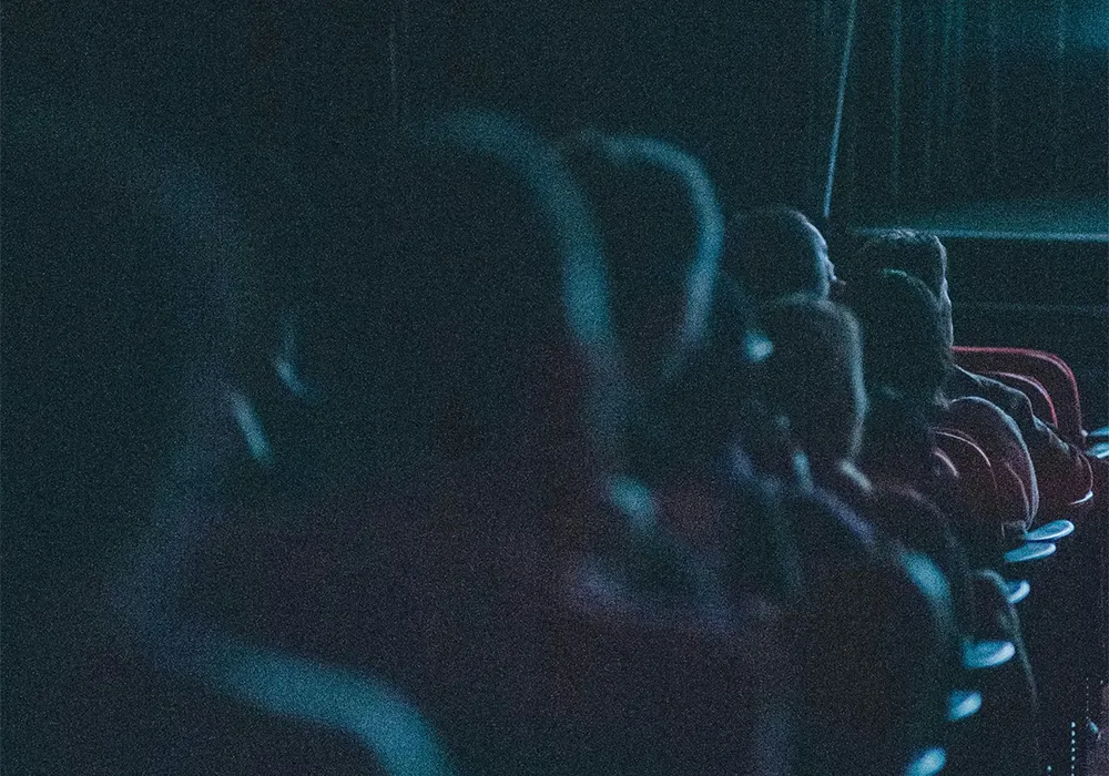 sff-arts-bg Audience seated in dark theatre with blue lighting illuminating their faces.