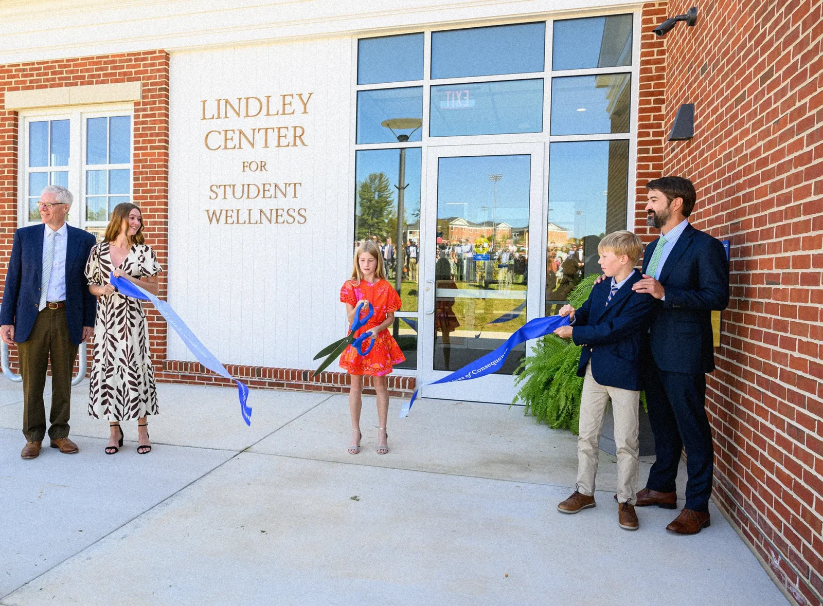 A young girl flanked on either side by family members, cuts a ribbon to open a health clinic called the Lindley Center for Student Wellness.